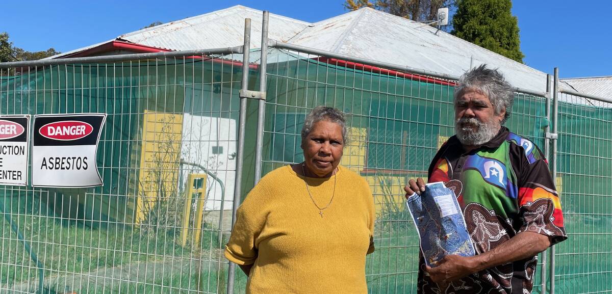 Deanna and Kenneth Campbell outside one of several asbestos-contaminated sites at their village on Wallaga Lake. Although this one has been fenced off, others have not. Mr Campbell is holding the EPA's map of the contaminated sites it has identified. Picture by Marion Williams