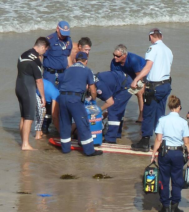 Emergency crews help a man rescued from a rip at Denhams Beach on March 12. A surfer saved the man's life and volunteer patrols also rescued 25 people in the shire this summer.