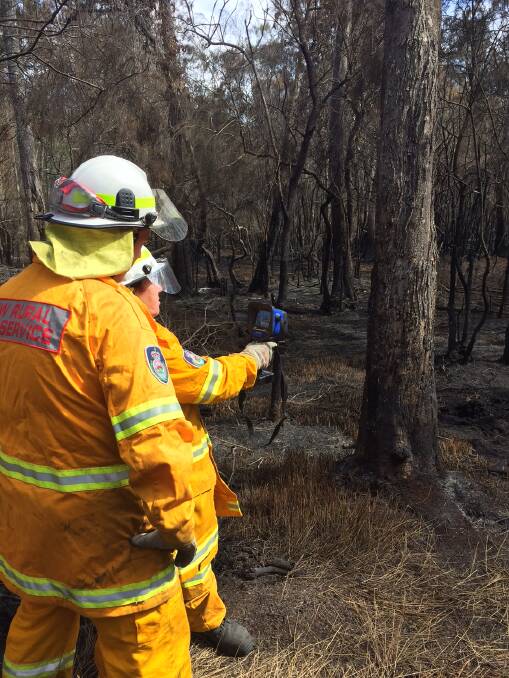 HIGH-TECH SPOTTING: Firefighters Jenn O'Brien and Brodie Carrington, from the Moruya branch of the NSW Rural Fire Service, use infra-red technology to find hot-spots in the duff-layer, after a fire on South Head Road, on January 8.