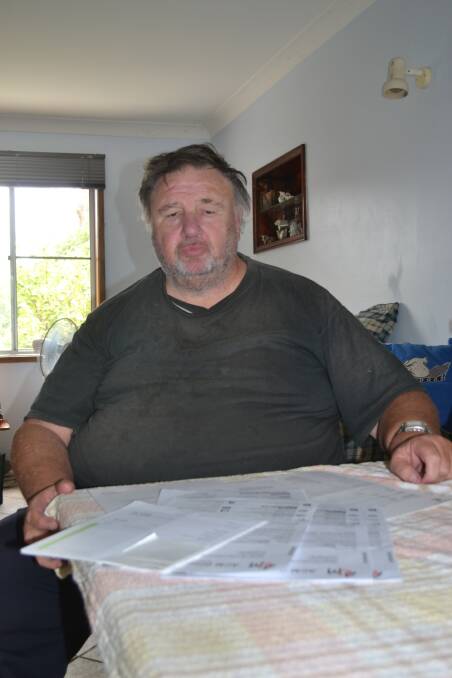 PAPER TRAIL: Nowra man Trevor Dale with the numerous letters he has received by companies trying to recover an outstanding Telstra bill.